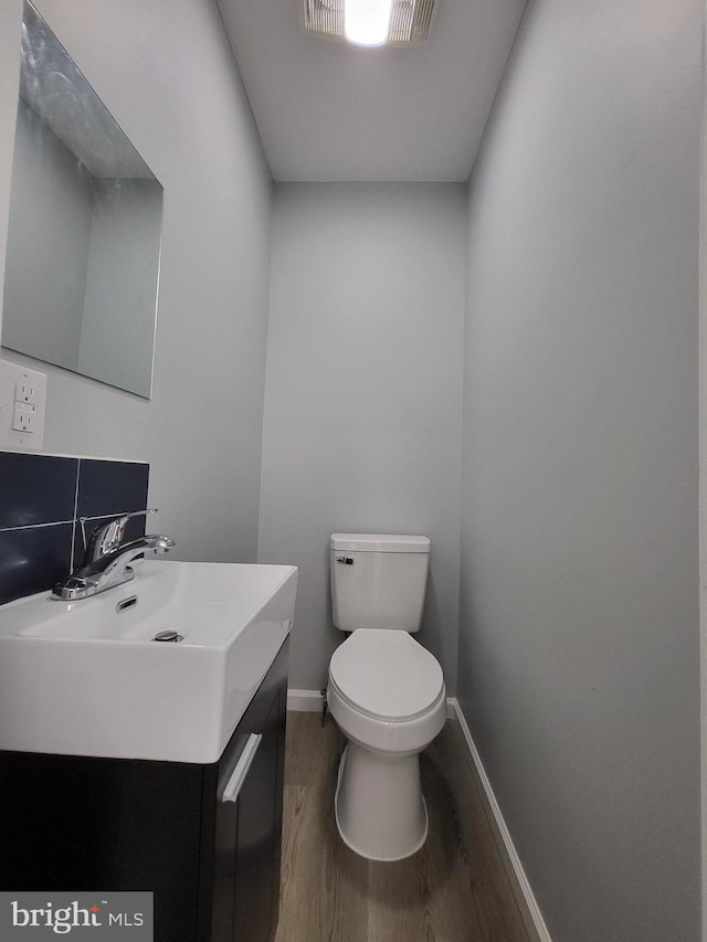 bathroom with vanity, hardwood / wood-style floors, decorative backsplash, and toilet