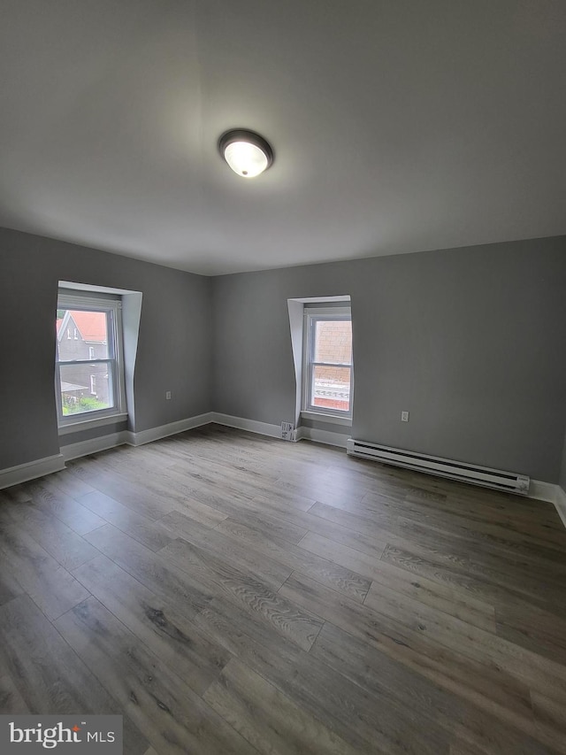 spare room featuring wood-type flooring and a baseboard heating unit