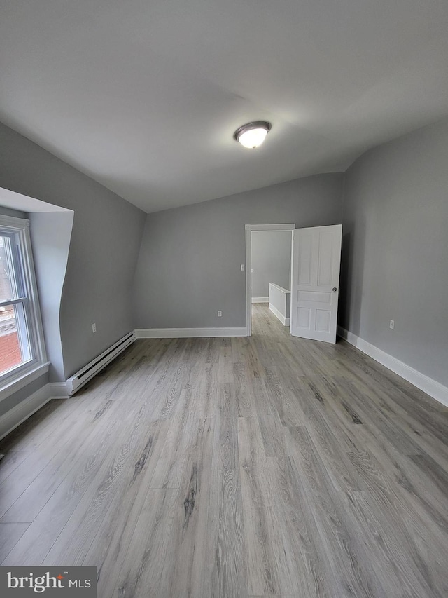 interior space with lofted ceiling, baseboard heating, and light hardwood / wood-style flooring