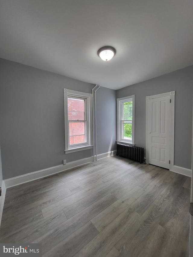 unfurnished room featuring radiator heating unit and hardwood / wood-style floors