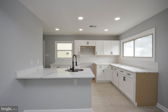 kitchen with sink, white cabinetry, light tile patterned floors, and kitchen peninsula