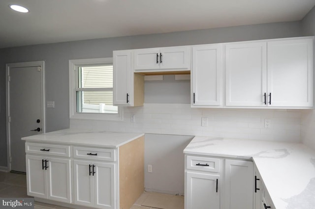 kitchen featuring white cabinetry, light stone counters, tasteful backsplash, and light tile patterned floors