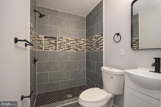 bathroom with vanity, a tile shower, and toilet