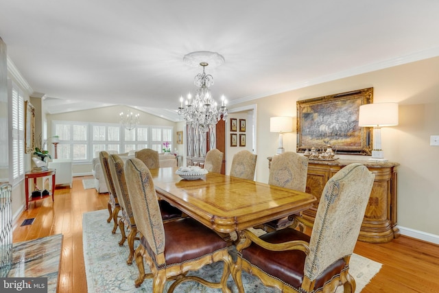 dining area with light hardwood / wood-style floors, ornamental molding, a chandelier, and vaulted ceiling