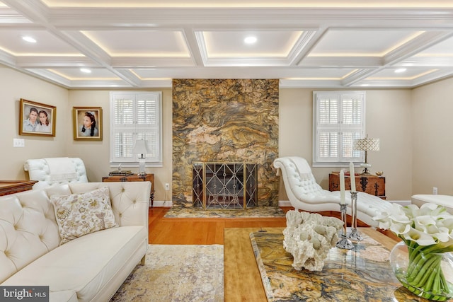 living room featuring coffered ceiling, hardwood / wood-style floors, beamed ceiling, and a stone fireplace