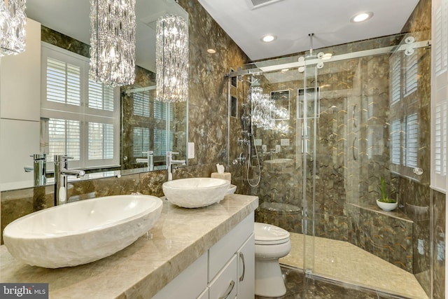 bathroom featuring vanity, tile walls, toilet, a notable chandelier, and a shower with shower door