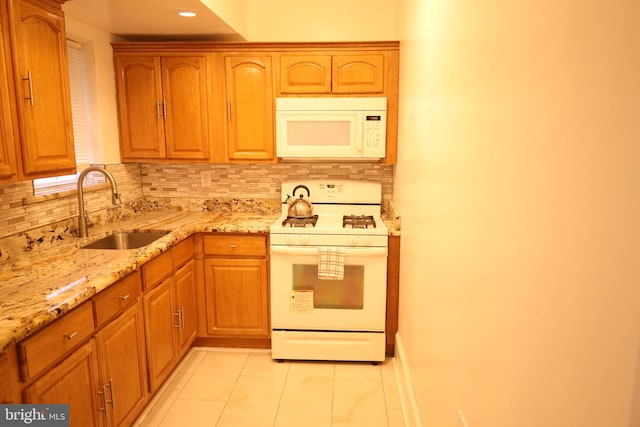 kitchen featuring light tile patterned flooring, white appliances, sink, decorative backsplash, and light stone countertops