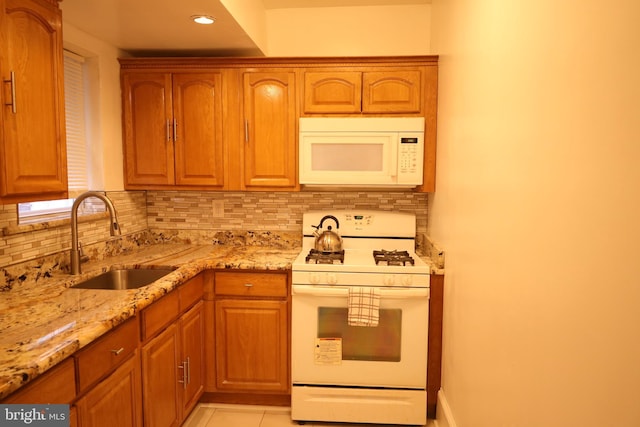 kitchen featuring light stone counters, decorative backsplash, white appliances, sink, and light tile patterned flooring