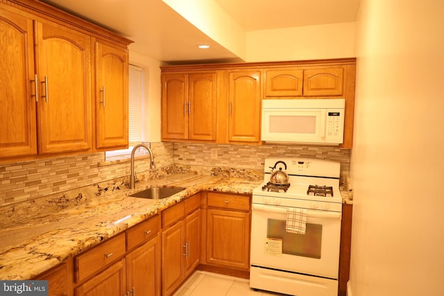 kitchen with light tile patterned floors, sink, white appliances, backsplash, and light stone countertops