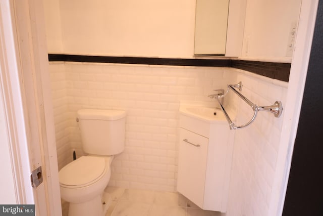 bathroom with tile patterned flooring, toilet, vanity, and tile walls