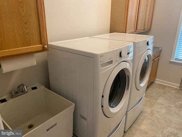 laundry room with sink, washing machine and dryer, and cabinets