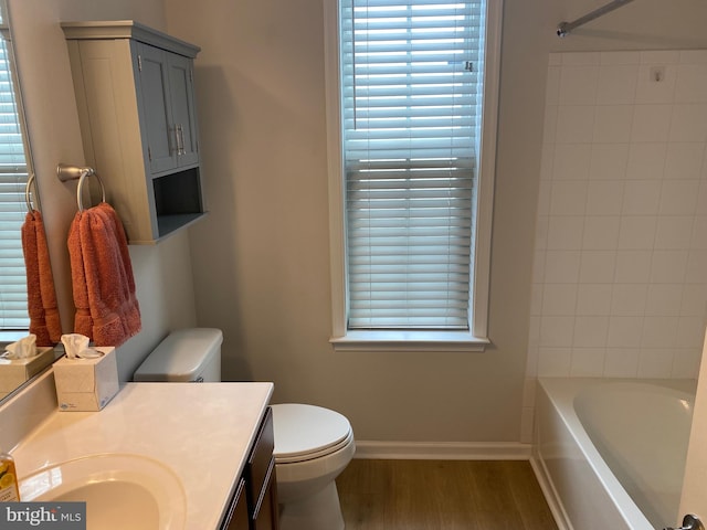 full bathroom with toilet, tiled shower / bath combo, hardwood / wood-style flooring, and vanity