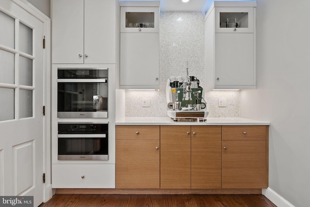 kitchen featuring white cabinets, double oven, and decorative backsplash