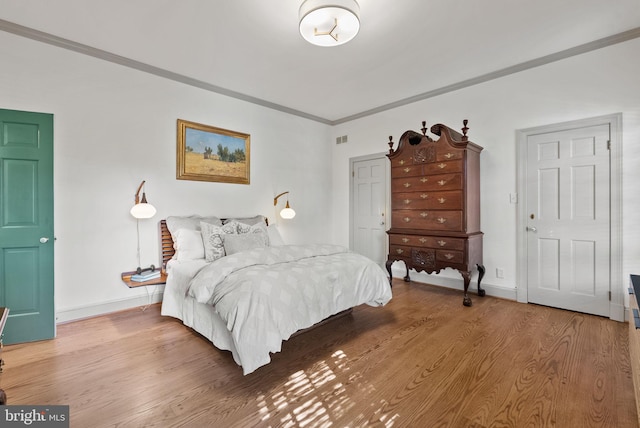 bedroom with hardwood / wood-style flooring and crown molding