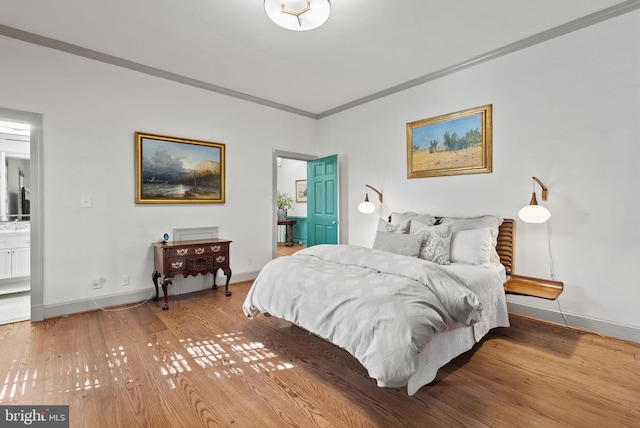 bedroom featuring wood-type flooring, ornamental molding, and ensuite bathroom