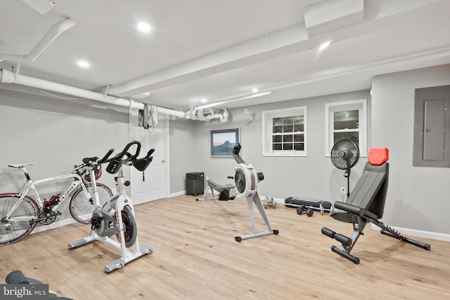 workout room with light hardwood / wood-style flooring and electric panel