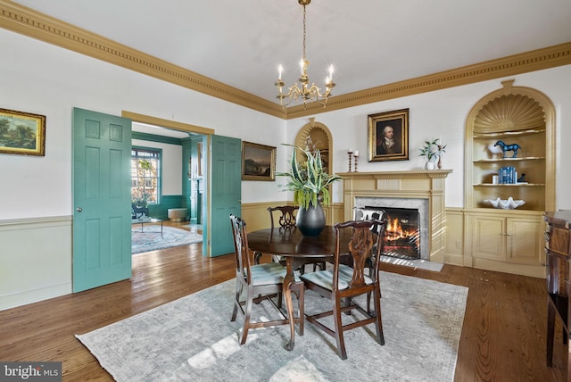 dining area with crown molding, a fireplace, hardwood / wood-style floors, and built in features