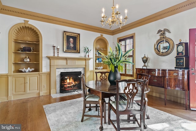 dining space with a chandelier, built in features, a high end fireplace, and light hardwood / wood-style flooring