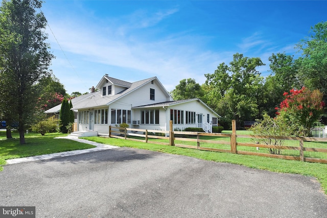 country-style home featuring a sunroom and a front lawn