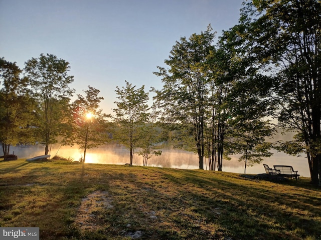 yard at dusk featuring a water view