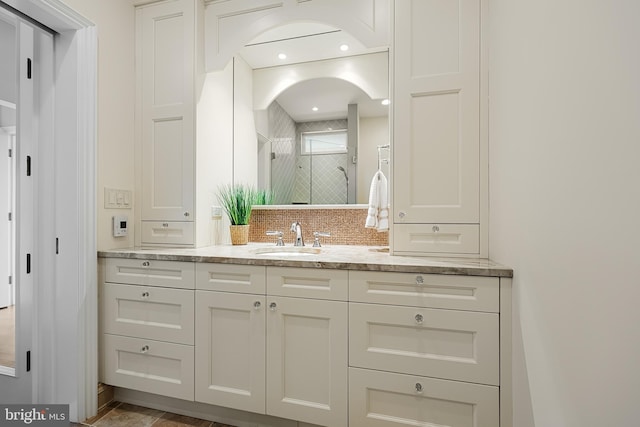 bathroom with vanity, backsplash, and a shower with shower door