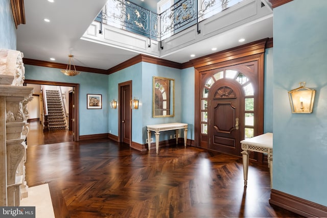 entryway with dark parquet flooring and ornamental molding