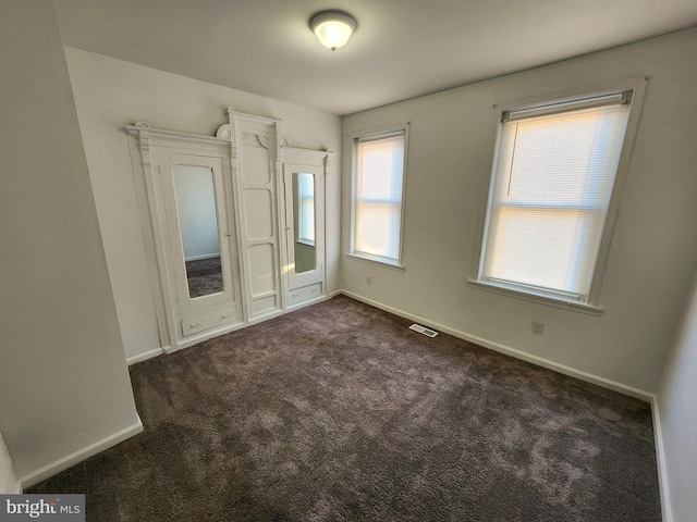 empty room featuring dark colored carpet