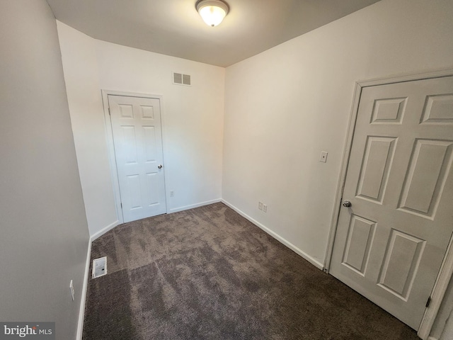 spare room featuring dark colored carpet