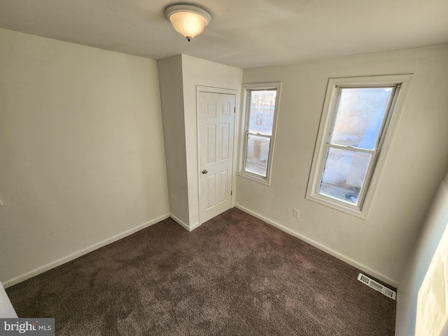 unfurnished bedroom with dark carpet