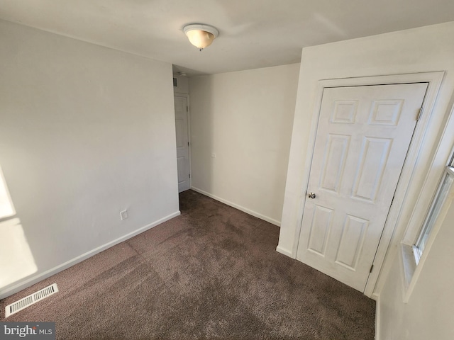 unfurnished room featuring dark carpet