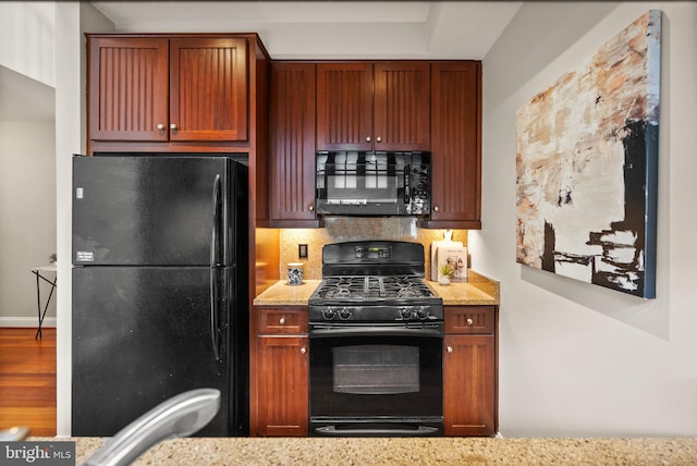 kitchen with black appliances, backsplash, hardwood / wood-style floors, and light stone counters