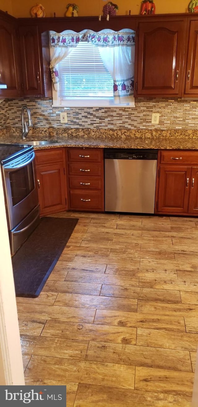 kitchen featuring tasteful backsplash, sink, light hardwood / wood-style floors, dishwasher, and electric range