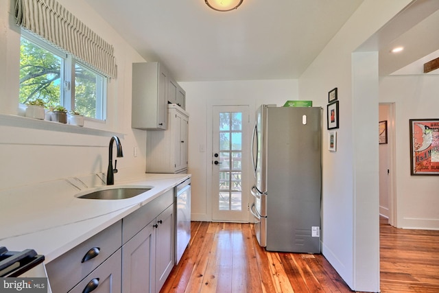 kitchen featuring gray cabinetry, sink, light hardwood / wood-style flooring, and appliances with stainless steel finishes