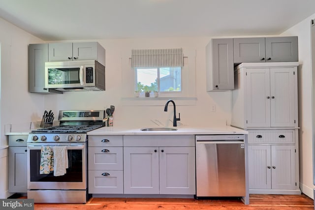 kitchen with gray cabinets, sink, and stainless steel appliances