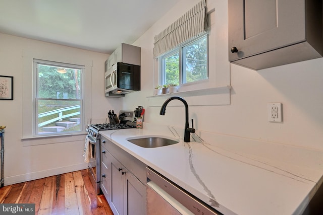 kitchen featuring light hardwood / wood-style flooring, stainless steel appliances, gray cabinets, and sink