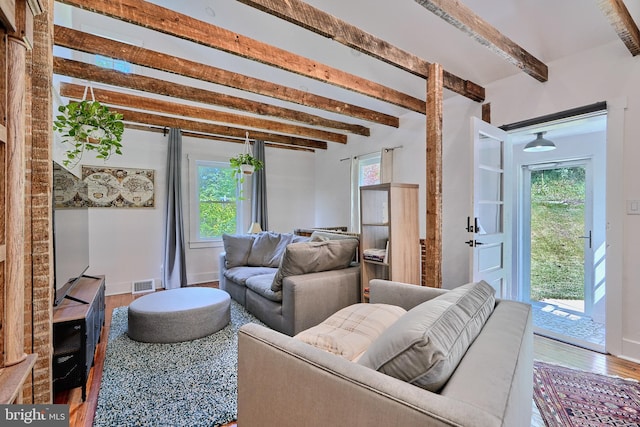 living room with hardwood / wood-style flooring, beam ceiling, and a healthy amount of sunlight