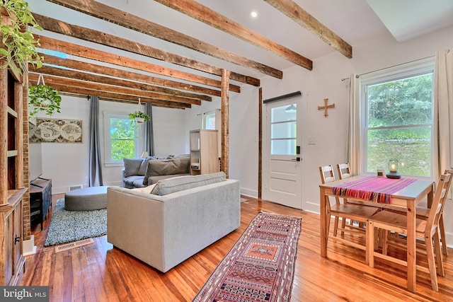 living room featuring beamed ceiling and light wood-type flooring