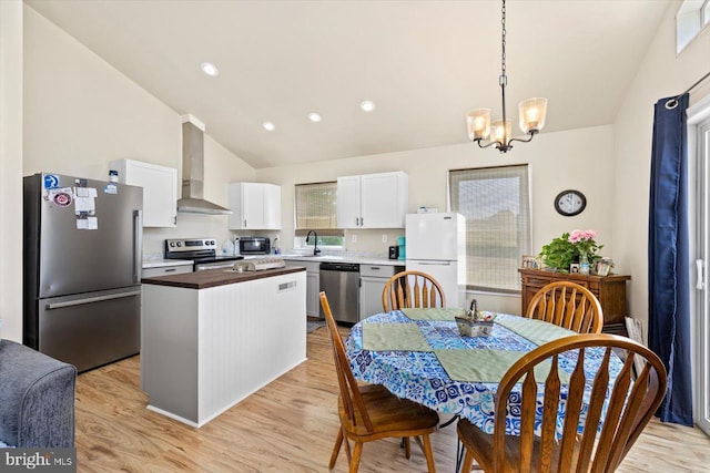 kitchen with appliances with stainless steel finishes, sink, white cabinets, a center island, and wall chimney exhaust hood