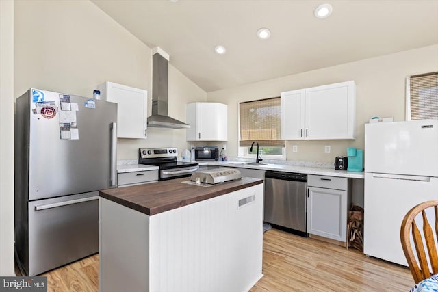 kitchen with a kitchen island, wood counters, white cabinets, stainless steel appliances, and wall chimney exhaust hood