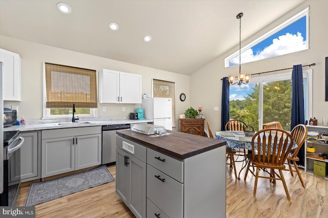 kitchen featuring lofted ceiling, sink, appliances with stainless steel finishes, light hardwood / wood-style floors, and decorative light fixtures