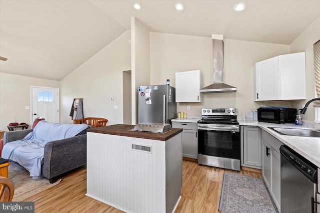 kitchen with wall chimney range hood, sink, white cabinets, and appliances with stainless steel finishes