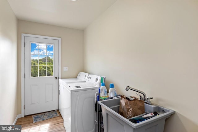 washroom with separate washer and dryer, sink, and light hardwood / wood-style floors