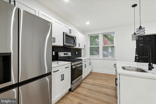 kitchen featuring white cabinetry, stainless steel appliances, light hardwood / wood-style flooring, and hanging light fixtures