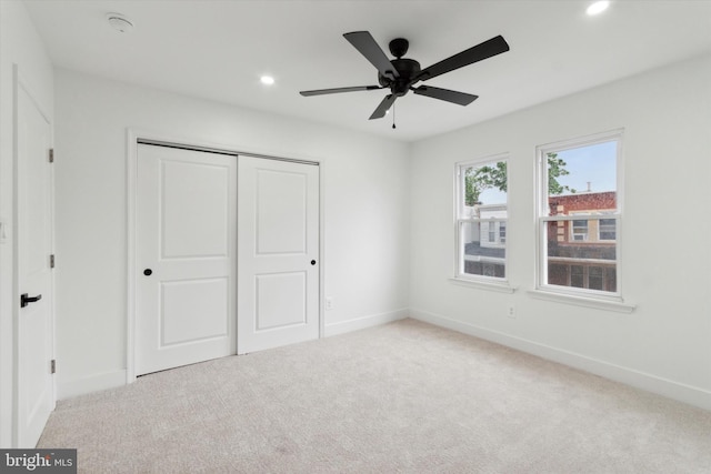 unfurnished bedroom featuring ceiling fan, light colored carpet, and a closet