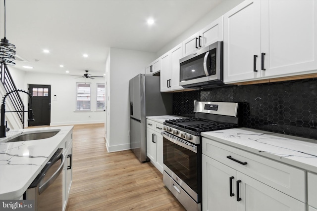 kitchen featuring light hardwood / wood-style flooring, light stone counters, backsplash, and stainless steel appliances