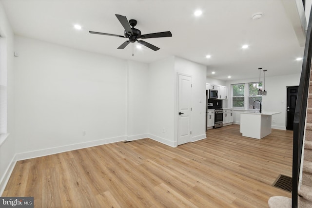 unfurnished living room featuring sink, light hardwood / wood-style flooring, and ceiling fan