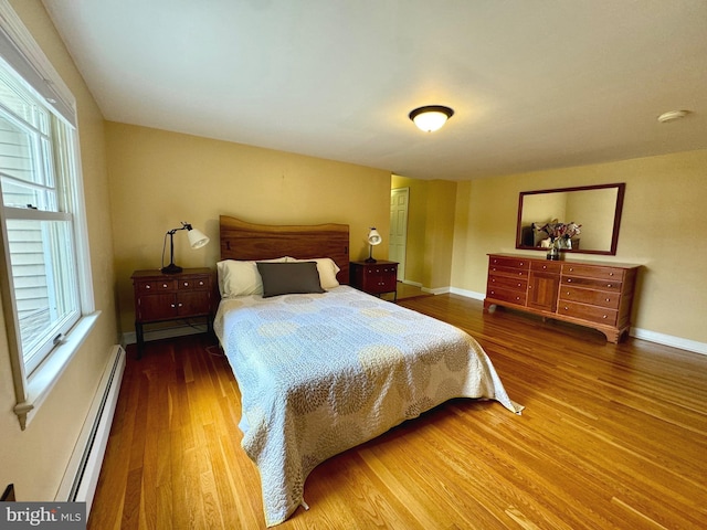 bedroom featuring hardwood / wood-style flooring and a baseboard heating unit