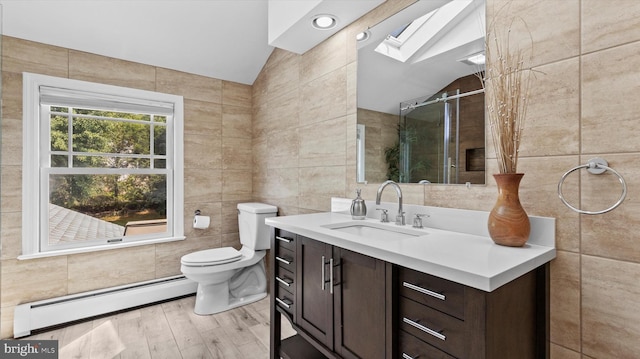 bathroom with lofted ceiling with skylight, tile walls, baseboard heating, vanity, and hardwood / wood-style floors