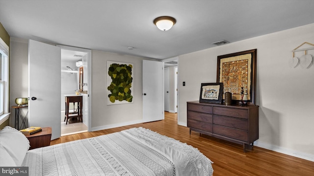 bedroom with hardwood / wood-style flooring and connected bathroom