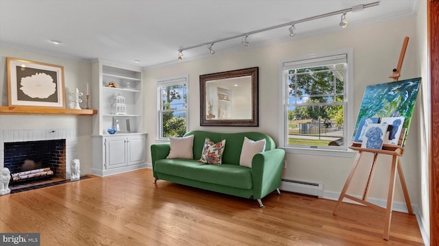 sitting room featuring track lighting, a wealth of natural light, a fireplace, and baseboard heating